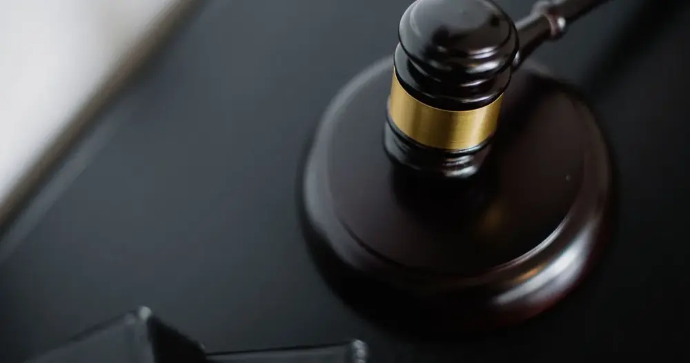 Martelo de madeira escura com detalhe dourado sobre uma mesa, símbolo do processo de interdição de idoso com demência