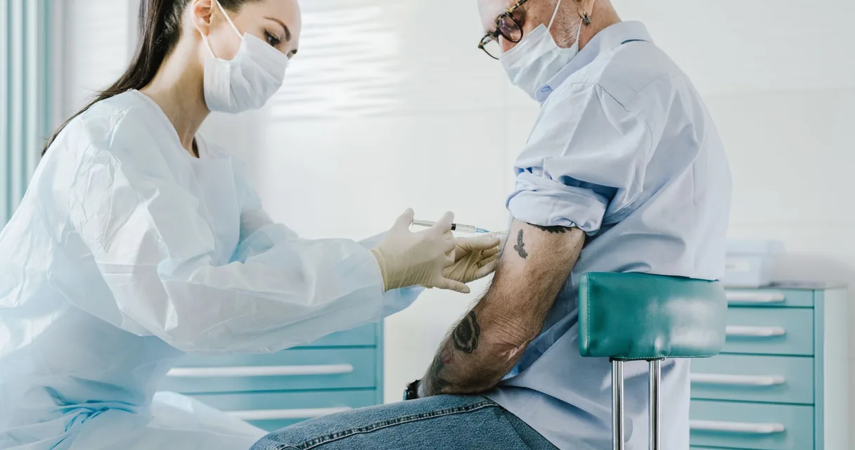 Profissional de saúde aplicando vacina no braço de um homem