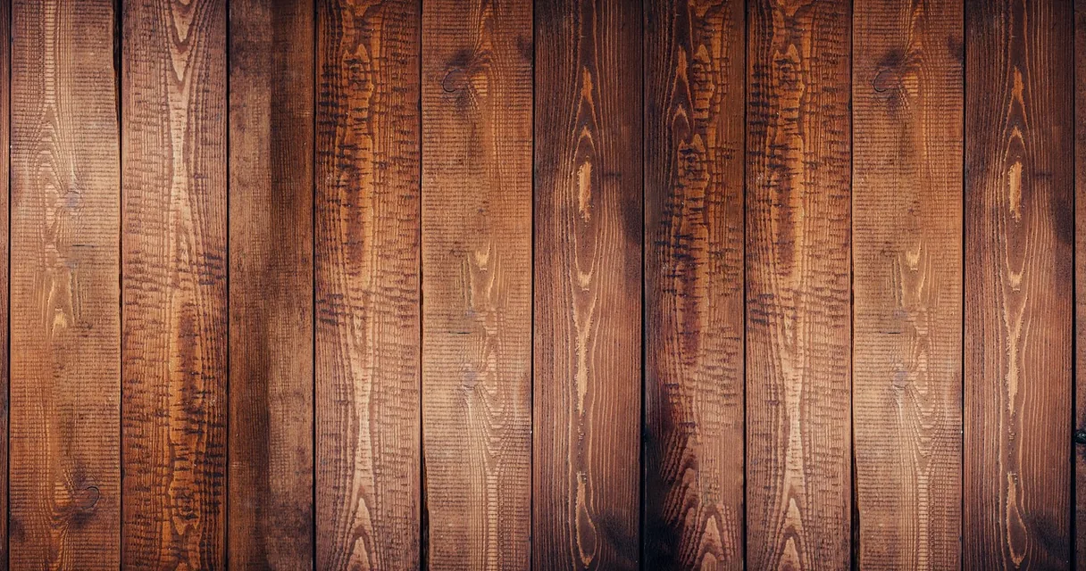 Tábuas de madeira escura lado a lado, ilustrando piso laminado estufado como consertar